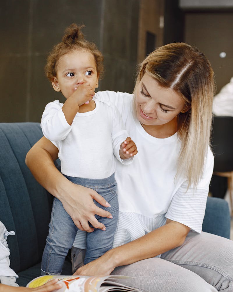 Caregiver holding a Bible, smiling with a child beside her